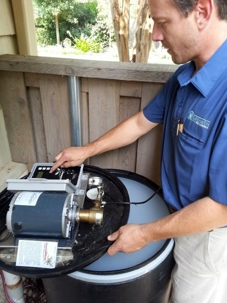 A professional adjusts the control panel of an outdoor mosquito misting system.